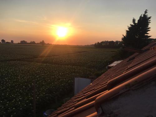 a sunset over a farm field with the sun setting at Authentic Farmhouse, near beach in Kloosterzande