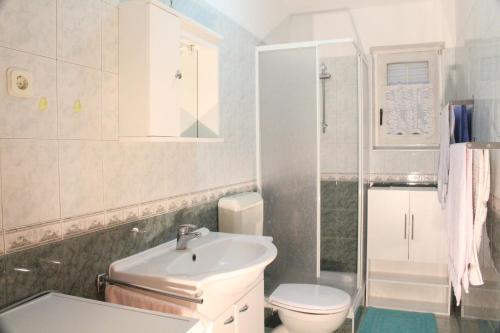 a white bathroom with a toilet and a sink at Haus Mandarina in Rab