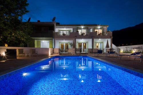 a swimming pool in front of a house at night at Luxurious Apartments Aria in Budva