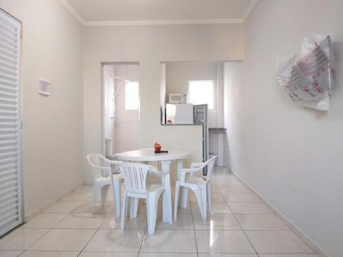 a kitchen with a white table and white chairs at Apartamento / Kitnetes in Peruíbe