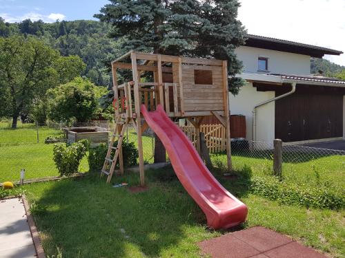 a playground with a red slide in a yard at Green Hill Apartments - Feldkirch in Feldkirch