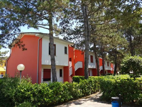 a row of orange and white buildings with trees at Adriella apartments in Bibione