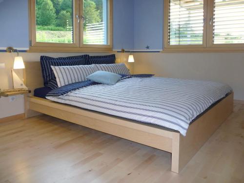 a large bed in a bedroom with two windows at Haus Bodenseeblick in Bodman-Ludwigshafen