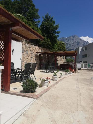a patio with chairs and a pavilion with mountains in the background at Apartments Malou in Baška Voda