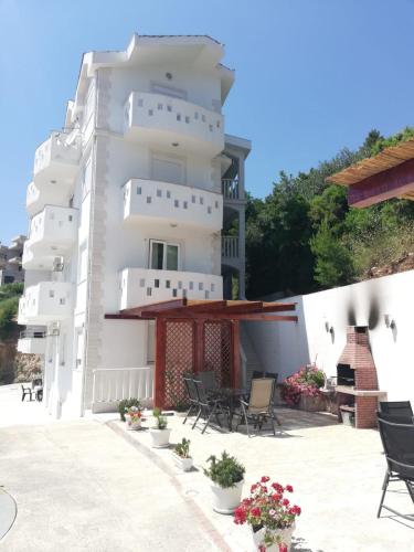 a large white building with chairs and flowers at Apartments Malou in Baška Voda