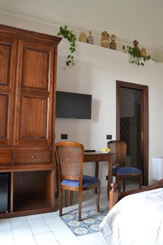 a bedroom with a table and chairs and a wooden cabinet at BnB Agorà Panoramic Rooms in Sciacca