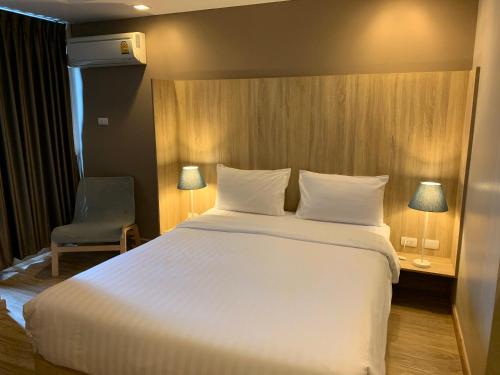 a bedroom with a large white bed and a chair at Baan Tanwa - MRT Ratchadapisek in Bangkok