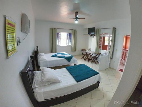 a bedroom with two beds and a dining room at Pousada Xodó da Praia in São Pedro da Aldeia