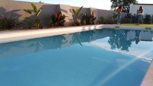 a blue swimming pool with people standing next to a building at Vila Milreu Guest House in Estói