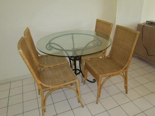a glass table with three wicker chairs and a glass table with a glass top at Paradise Lagoon Apartment in Port Dickson