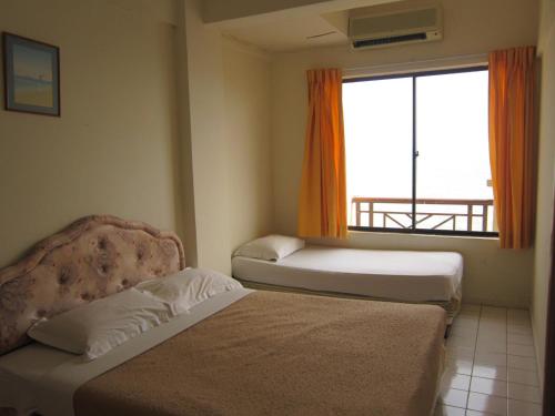 a hotel room with two beds and a window at Paradise Lagoon Apartment in Port Dickson