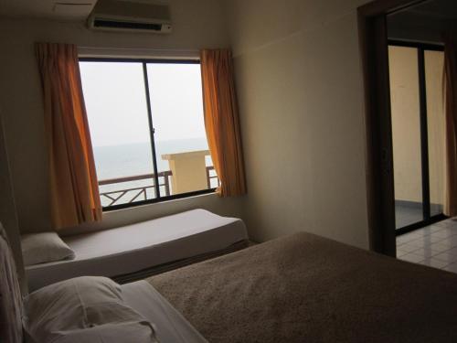 a bedroom with two beds and a view of the ocean at Paradise Lagoon Apartment in Port Dickson
