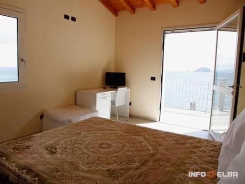 a bedroom with a bed and a television and a window at B&B LE FORNACELLE in Rio Marina