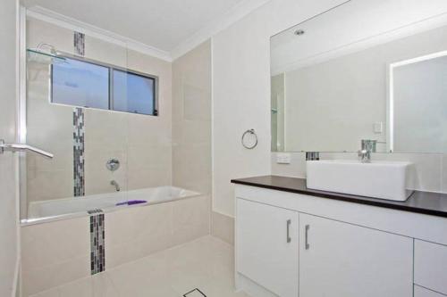 a bathroom with a tub and a sink and a mirror at Casuarina Beach House by Kingscliff Accommodation in Kingscliff
