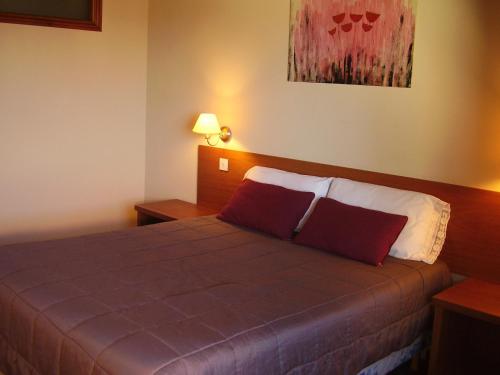 a hotel room with a bed with two red pillows at Departamentos Altos del Centro in San Carlos de Bariloche