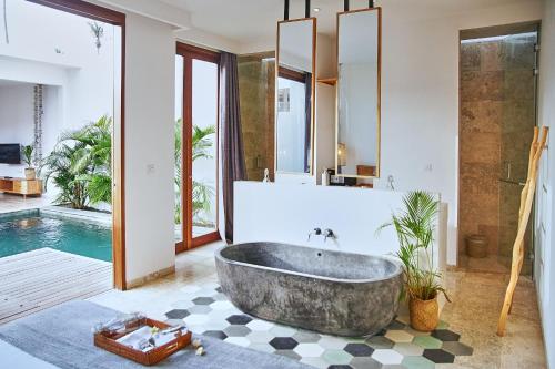 baño con bañera grande y piscina en Kumbara Villas en Kuta Lombok