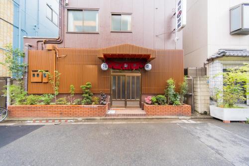 un edificio con una puerta y flores delante en Tokyo SA Ryokan, en Tokio