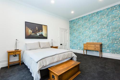 1 dormitorio con 1 cama y una pintura en la pared en The Stuart Street Terraced House en Dunedin