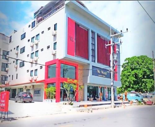 a large white building with red trim on a street at We World Boutique Haatyai in Hat Yai