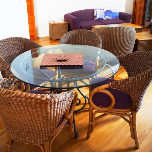 a glass table with wicker chairs around a glass table at Mantra on the Inlet in Port Douglas