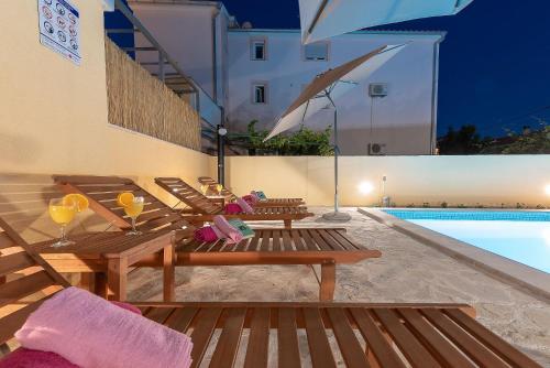 a group of wooden benches next to a swimming pool at Apartments Dijana in Zadar