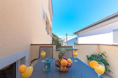 a table with a bowl of fruit and glasses of orange juice at Apartments Dijana in Zadar