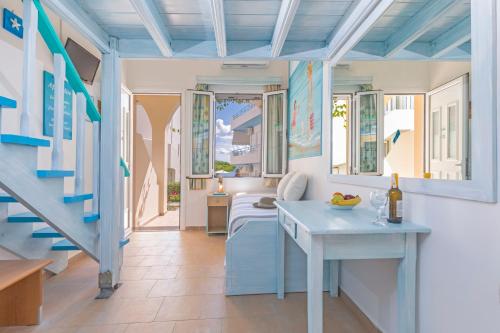 ein Zimmer mit einem Tisch und einigen Fenstern und einer Treppe in der Unterkunft Haraki Memories Beach Studios in Charaki