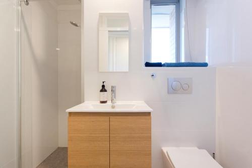 a white bathroom with a sink and a shower at Ocean Breeze Apartment in Fremantle