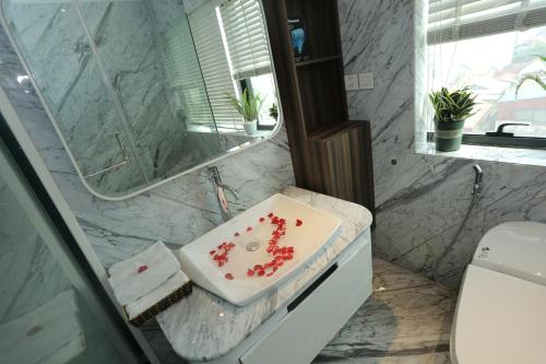 a bathroom with a white sink with red flowers on it at HNC Premier Hotel & Residences in Hanoi