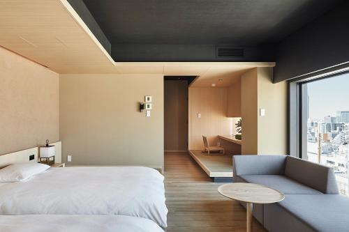 a bedroom with a bed and a couch and a window at ONSEN RYOKAN YUEN SHINJUKU in Tokyo