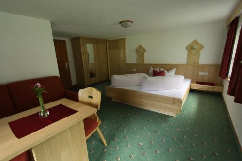 a hotel room with a bed and a table at Haus Bödele in Sankt Leonhard im Pitztal