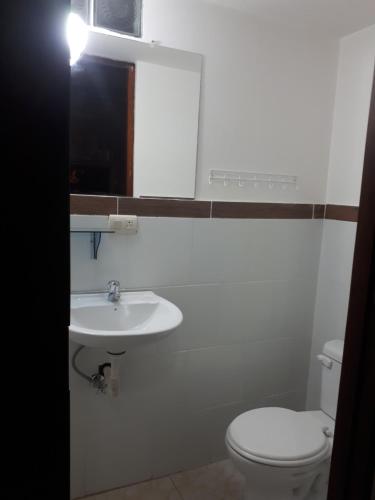 a bathroom with a white toilet and a sink at Hostal Villa Brisa in Ballenita