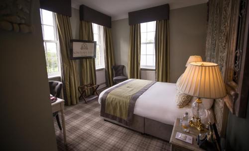 a hotel room with a bed and a lamp and windows at Bowburn Hall Hotel in Durham