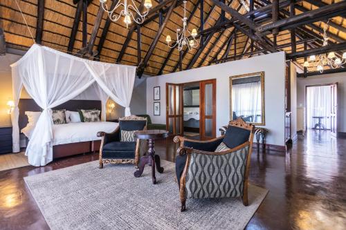a bedroom with a bed and a table and chairs at Epacha Game Lodge & Spa in Okaukuejo