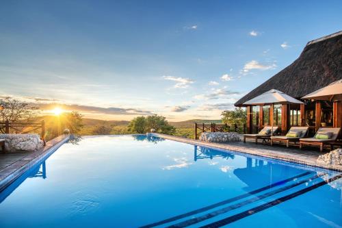 a pool with a view of a house at Epacha Game Lodge & Spa in Okaukuejo