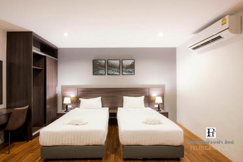 a bedroom with two beds and a desk at Feungfah Litz in Phetchabun