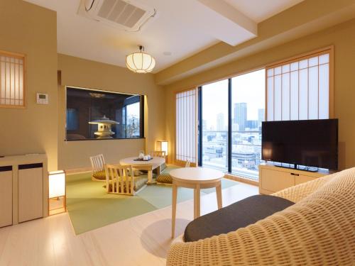 a living room with a couch and a tv at Osaka View Hotel Honmachi in Osaka