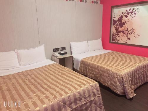 2 camas en una habitación de hotel con paredes rosas en Flower Motel, en Chiayi