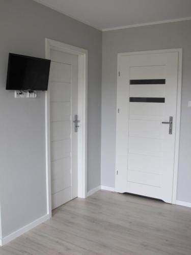 an empty room with a white door and a flat screen tv at Apartament Baltic in Sztutowo