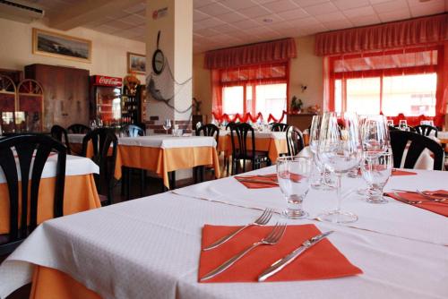 uma sala de jantar com mesas brancas com copos e guardanapos em Piccolo Hotel em Rosignano Solvay