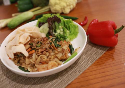 a white bowl of food with vegetables on a table at All Nite & Day Kebon Jeruk in Jakarta