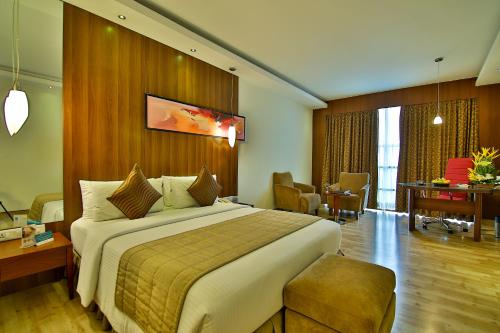 a hotel room with a large bed and a desk at Gokulam Park Coimbatore in Coimbatore