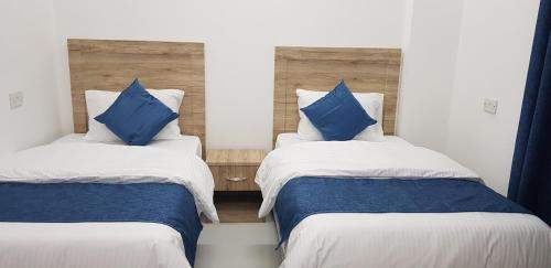 Duas camas num quarto com almofadas azuis em Duqm Suites em Duqm