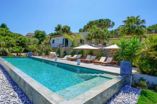 a pool with chairs and umbrellas next to a house at villa Sant-Anna in Saint-Tropez