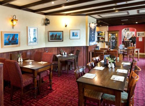 a restaurant with wooden tables and chairs in a room at Anchor Inn by Greene King Inns in Beer