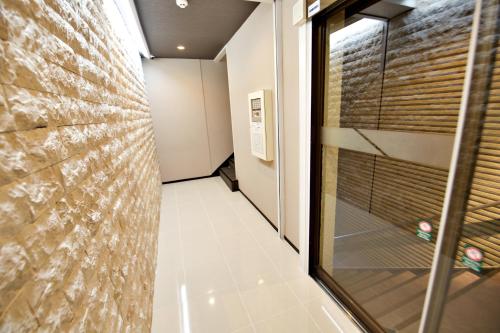 a hallway with a glass door and a brick wall at KURA HOTEL IZUMISANO in Izumi-Sano