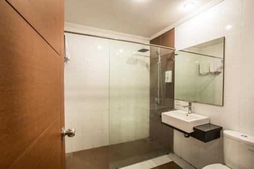 y baño con ducha, lavabo y espejo. en Svarna Hotel en Sanur