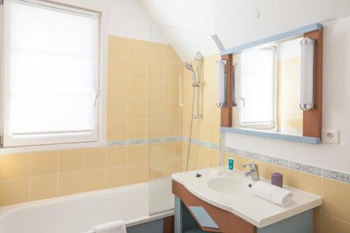 a bathroom with a sink and a tub and a mirror at Village Pierre & Vacances Belle Dune in Fort-Mahon-Plage