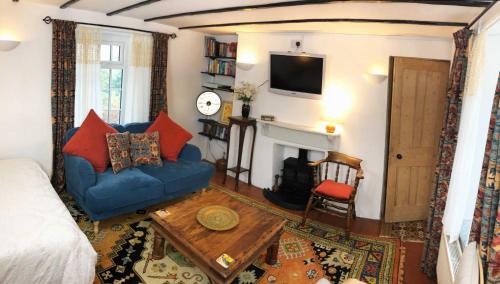 a living room with a blue couch and a fireplace at Central Boscastle studio flat in Boscastle