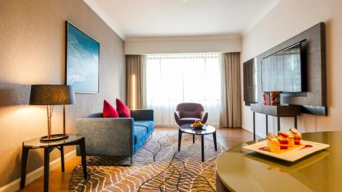 a living room with a blue couch and a table at Novotel Kuala Lumpur City Centre in Kuala Lumpur